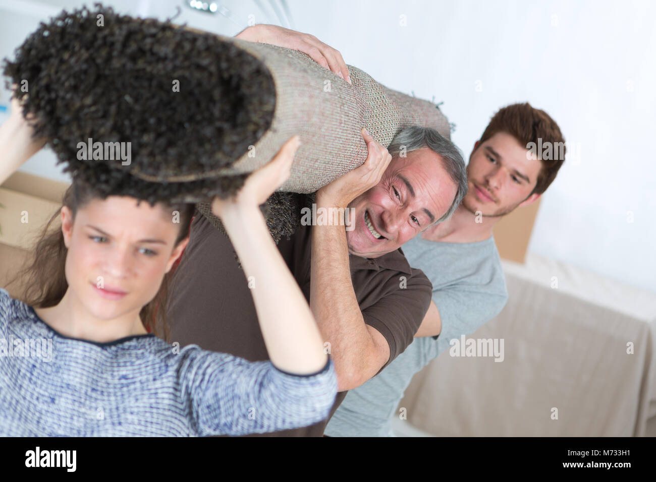 family lifting a heavy carpet Stock Photo Alamy