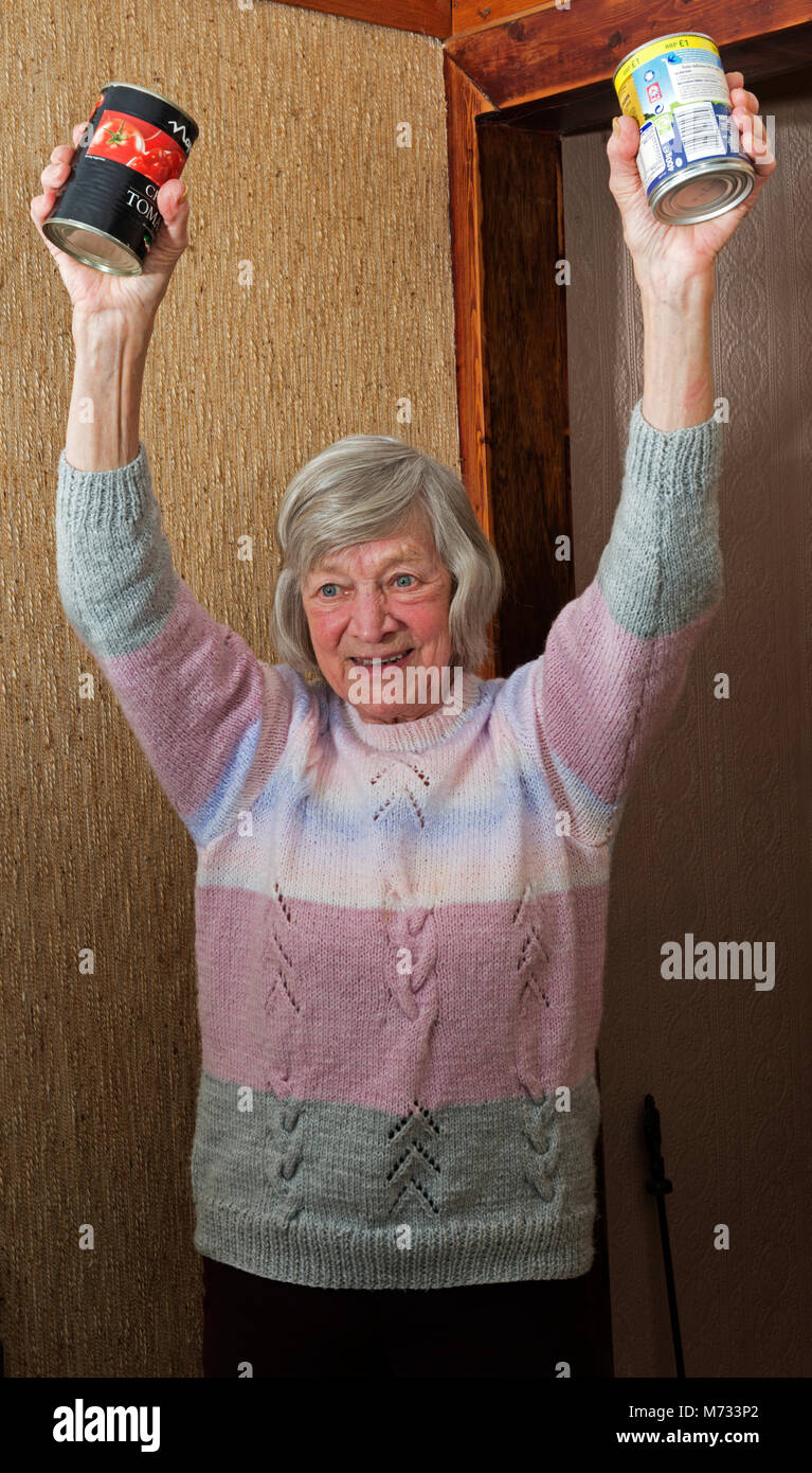 Elderly woman doing exercises using tinned food Stock Photo