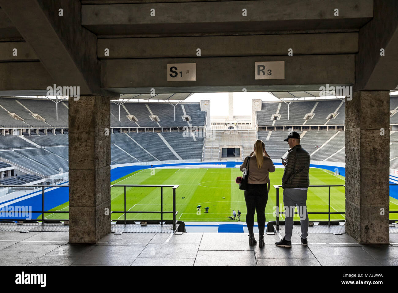 Couple of people take a picture of tribunes of Olympiastadion (Olympic Stadium) in Berlin, Germany Stock Photo