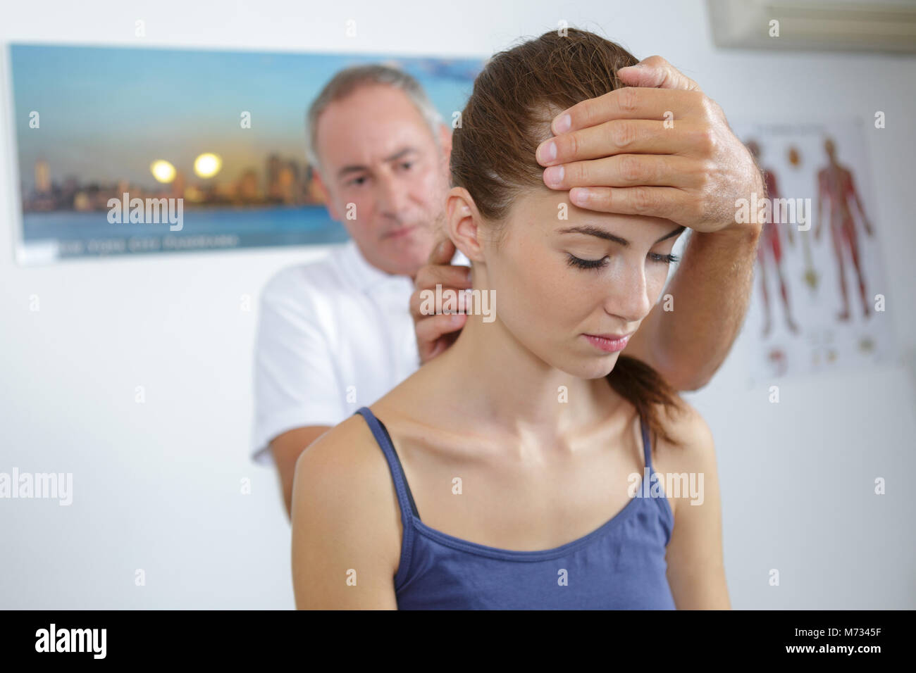 male physiotherapist giving head massage to female patient in clinic Stock Photo