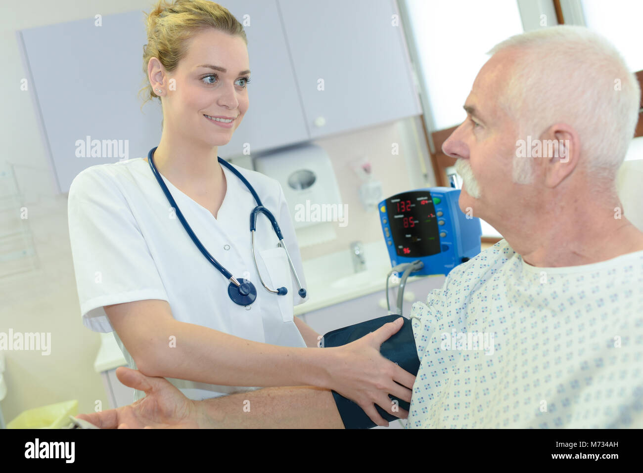 Nurse putting blood pressure testing cuff onto patient's arm Stock Photo