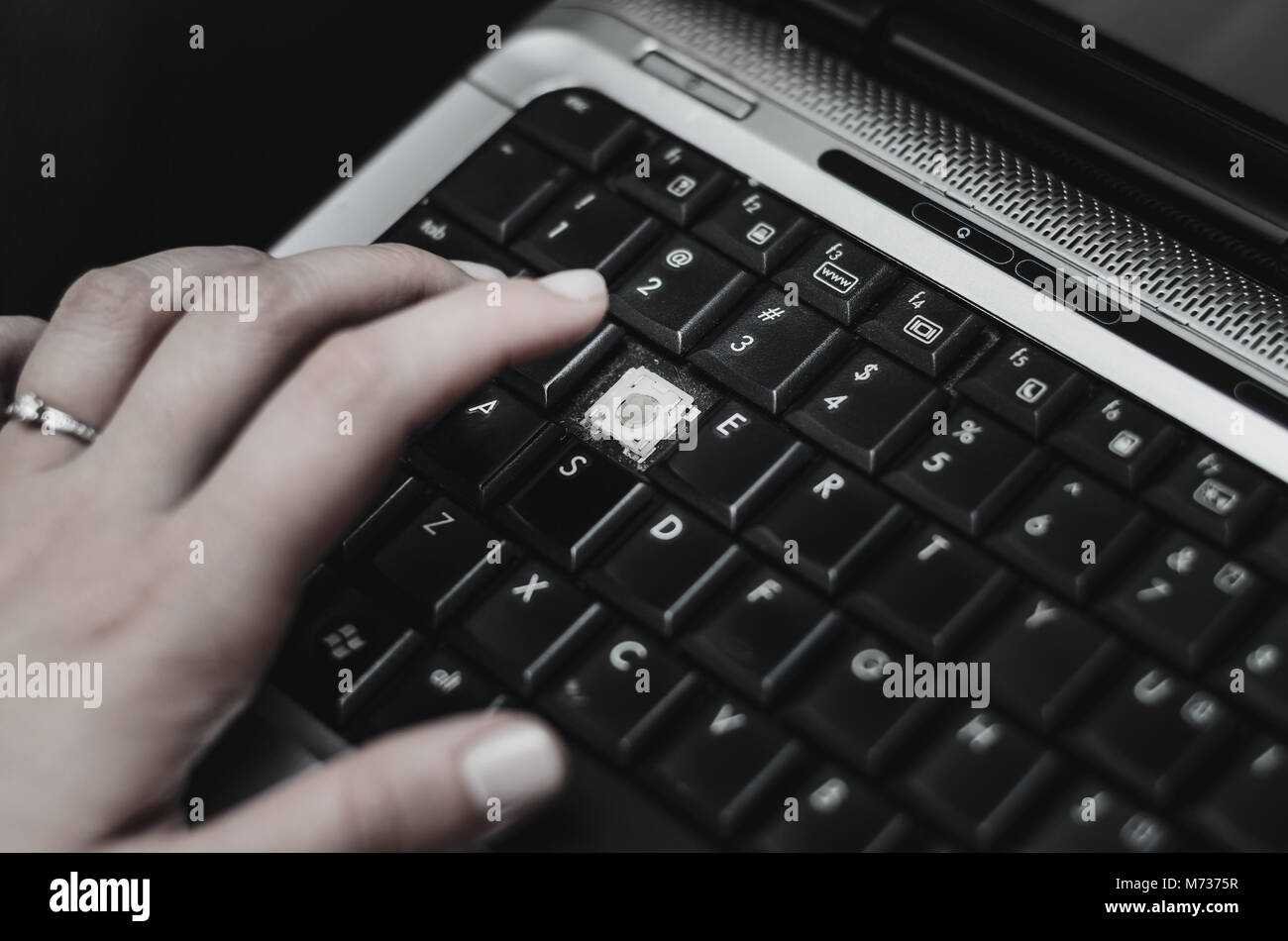 Hand of a woman over a laptop with a missing keyboard key. Broken keyboard key, need for maintenance. Stock Photo