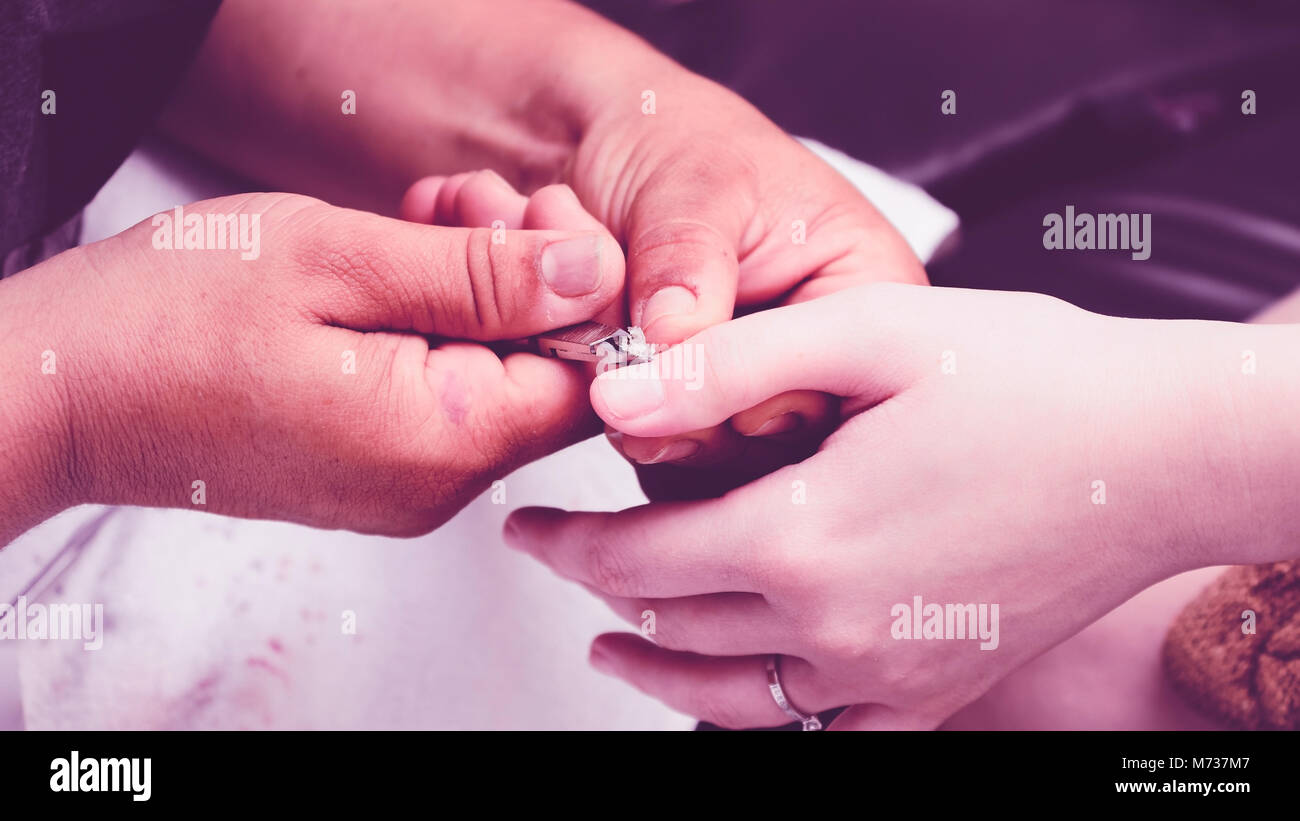 Manicurist using pliers to remove dead skin from around the client