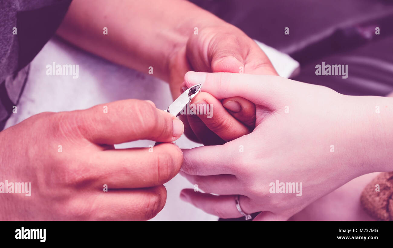 Manicurist using pliers to remove dead skin from around the client
