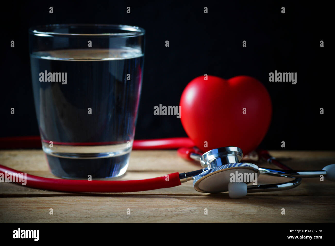Stethoscope and red heart with water on wood and black background Stock ...
