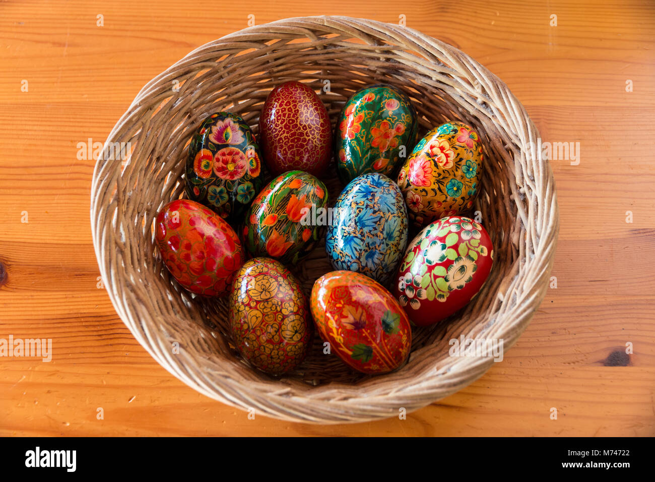 A basket with wooden eggs, painted with floral designs on a table, as