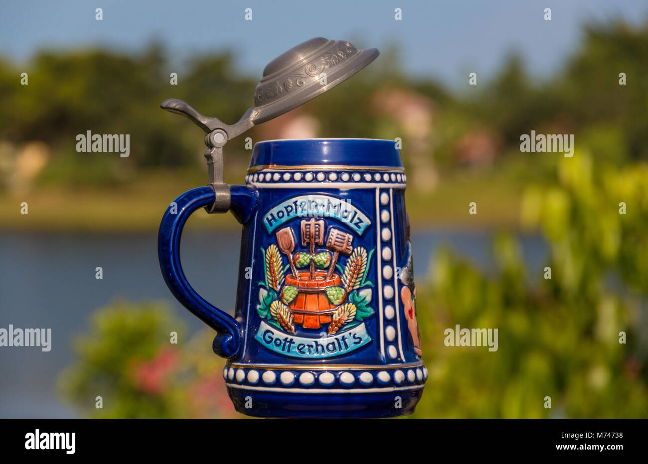 A German porcelain beer stein with a hinged pewter lid and there is a toast on it: 'Hopfen + Malz, Gott erhalt's'. Stock Photo
