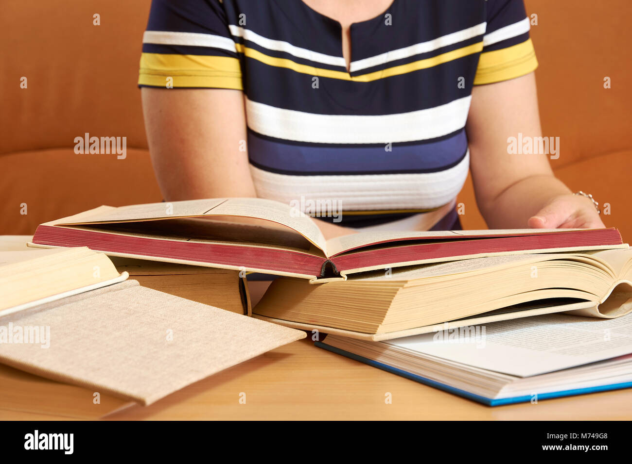 Sitting mature woman in a dress, reading a book Stock Photo
