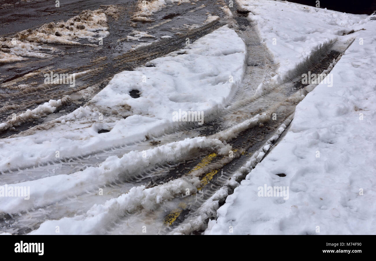 After snow come slush, car tyre marks left in snow Stock Photo