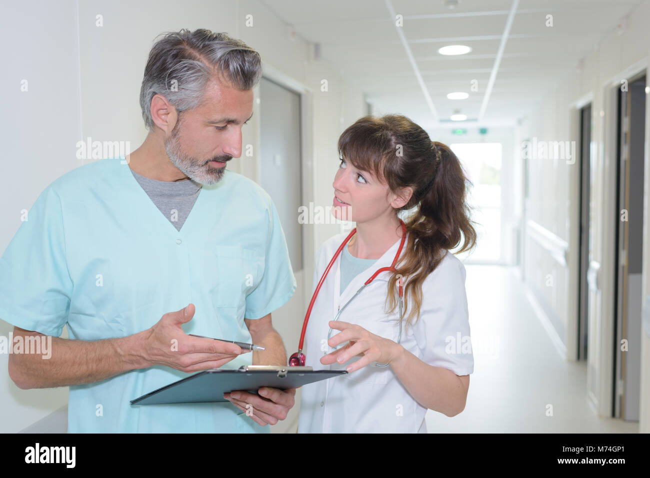 Medical staff discussing notes in hospital corridor Stock Photo - Alamy