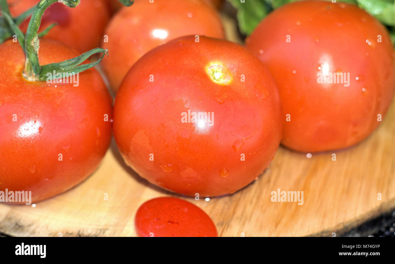 Juicy tomatoes of Roma variety. Organic Tomato is salad vegetable rich in vitamin c. Shot from angle, close up isolated tomatoes on wooden board Stock Photo