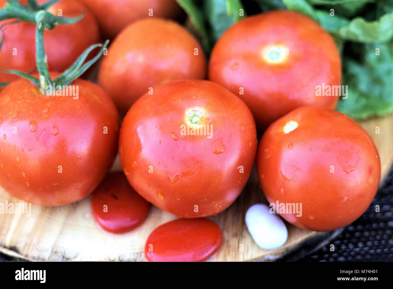 Juicy tomatoes of Roma variety. Organic Tomato is salad vegetable rich in vitamin c. Shot from angle, close up isolated tomatoes on wooden board Stock Photo