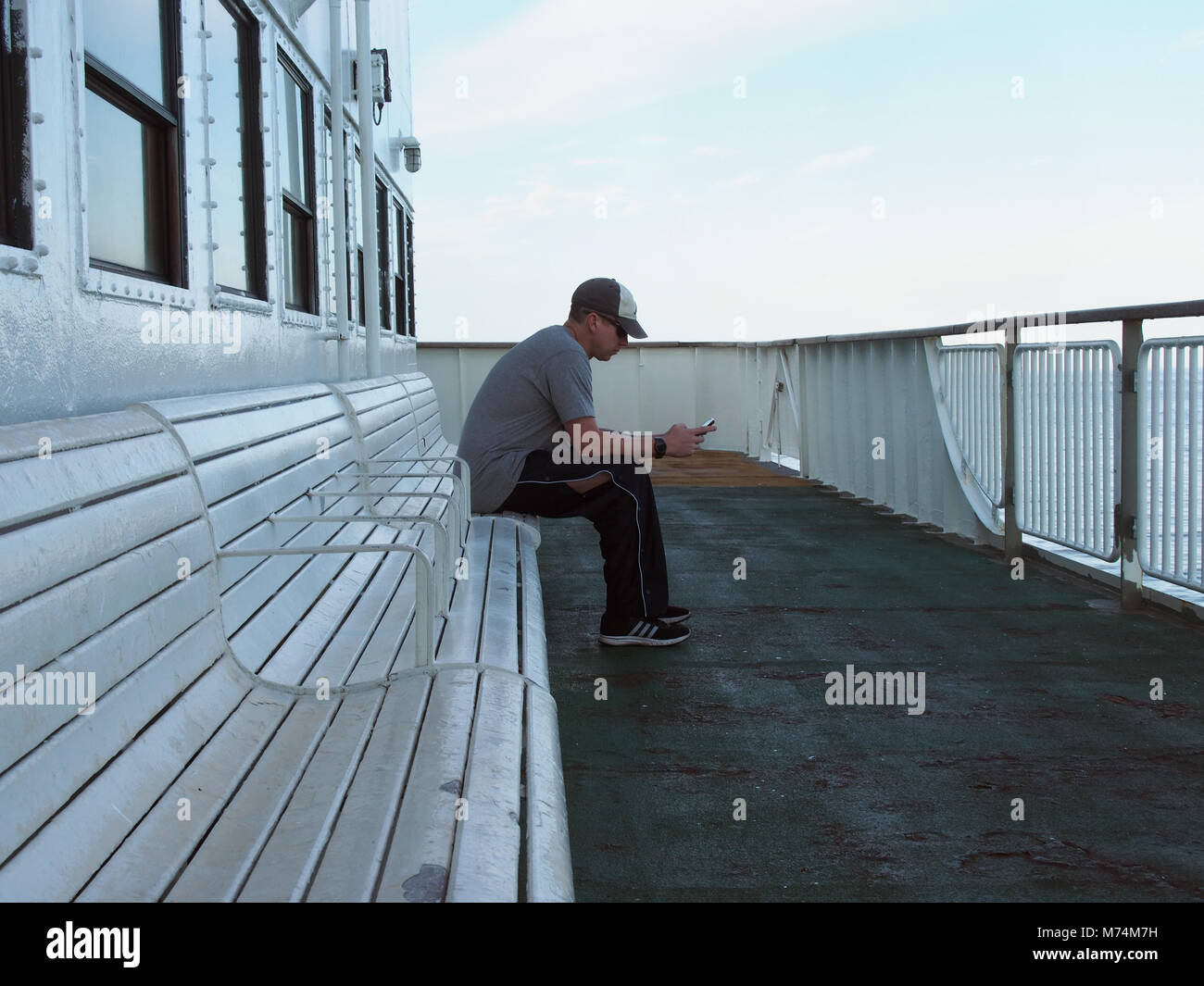 A man using his smartphone during an early summer morning ferry trip from Cape May NJ to Lewes DE, © Katharine Andriotis Stock Photo