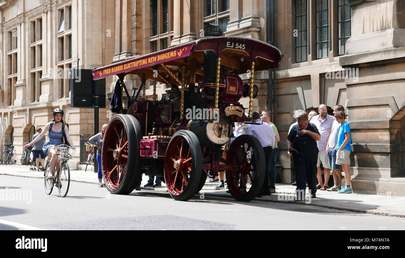 Traction Engine on Cambridge University street with female student cycling past Stock Photo