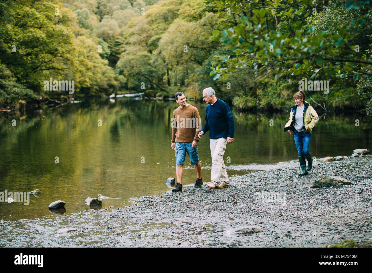 Mid adult man is enjoying a walk around the Lake District with his parents. He is walking with his father and his mother is just behind them. Stock Photo