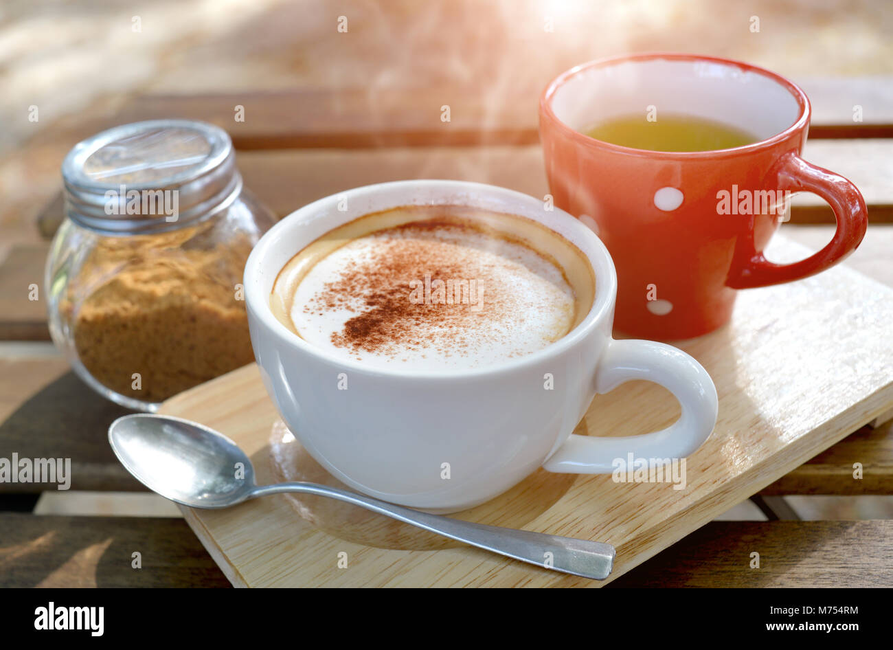Hot cappuccino coffee on the  wooden table style in outdoor morning low and soft lighting. Stock Photo