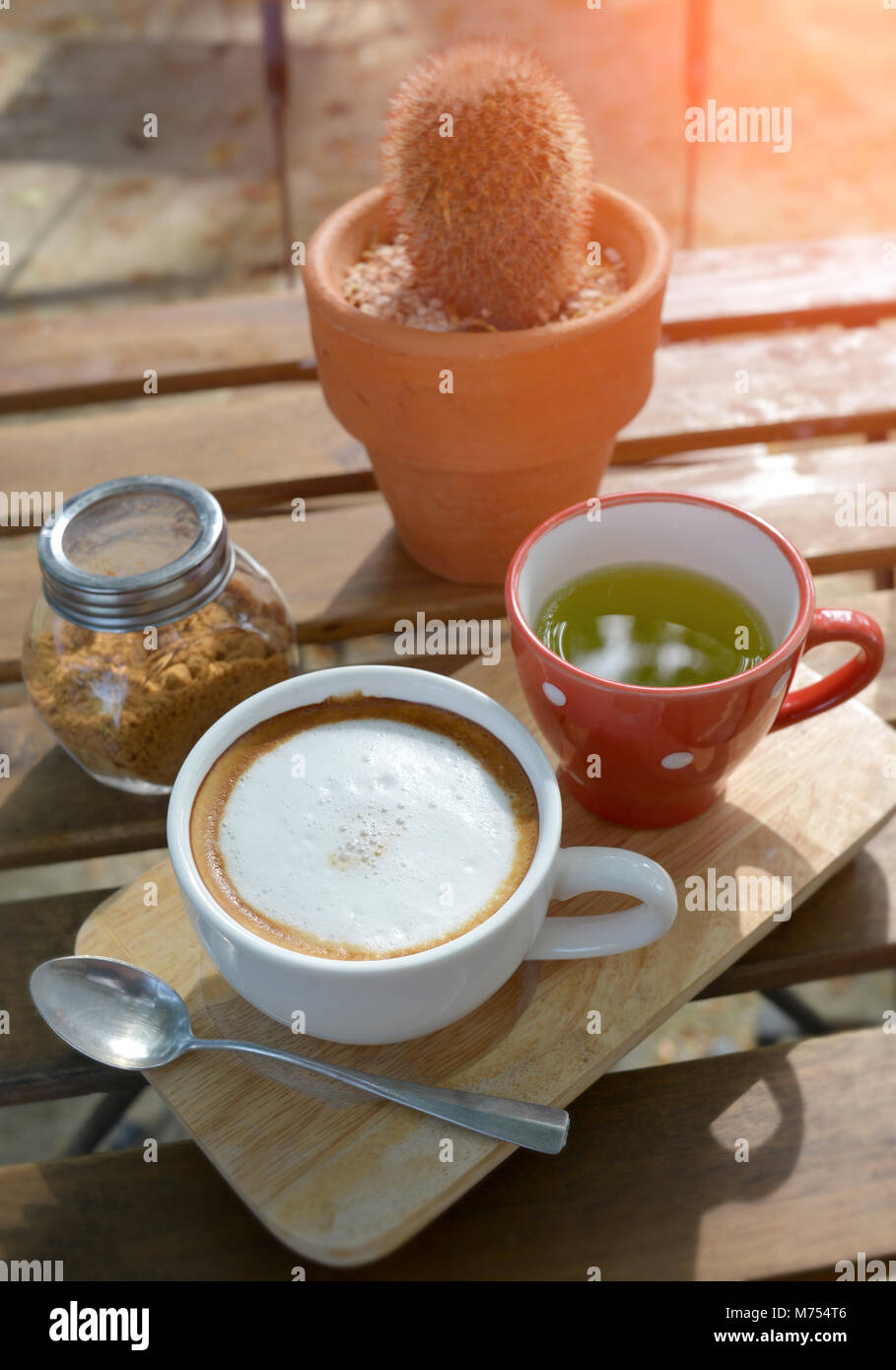 Hot cappuccino coffee on the  wooden table style in outdoor morning low and soft lighting. Stock Photo