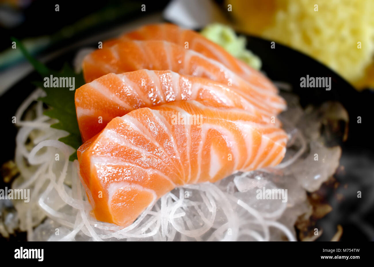 Raw salmon slice or salmon sashimi in Japanese style fresh serve on ice with fresh wasabi photo in  indoor low lighting. Stock Photo