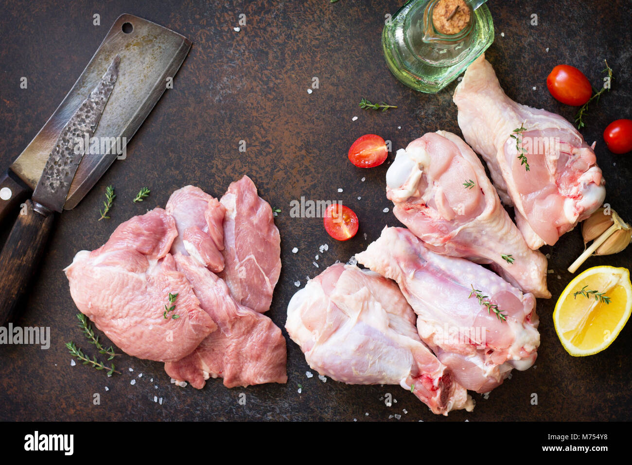 Fresh meat. Raw turkey shin, tomatoes, lemons and spices on a stone table. Stock Photo