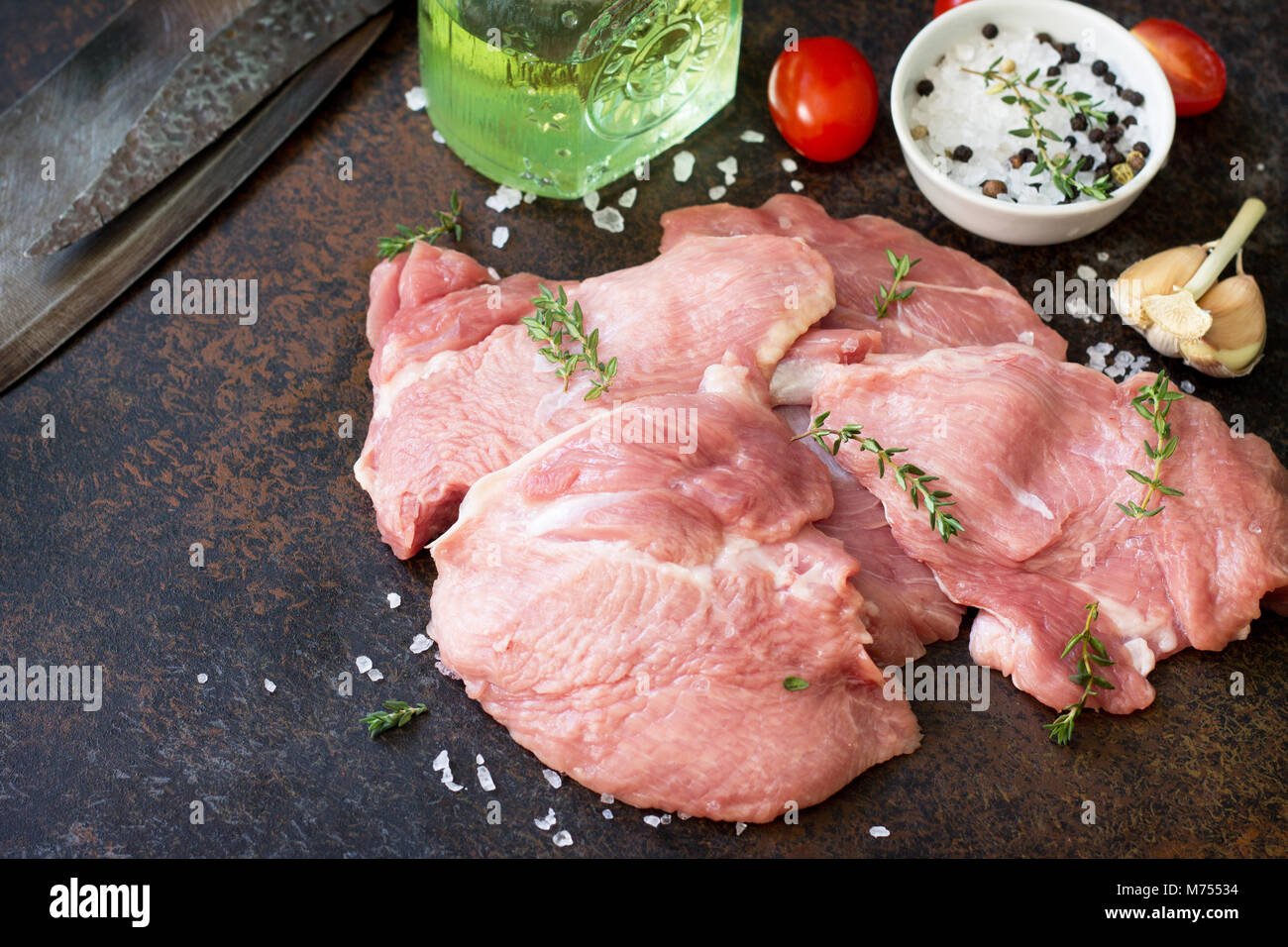 Fresh meat. Raw turkey shin, tomatoes, lemons and spices on a stone table. Stock Photo