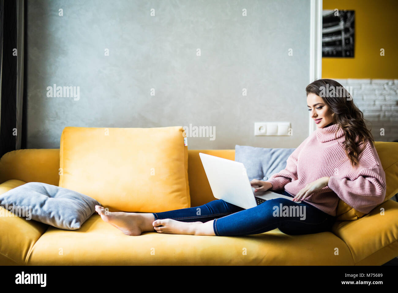 Beautiful happy smiling woman lying on the sofa with laptop Stock Photo ...