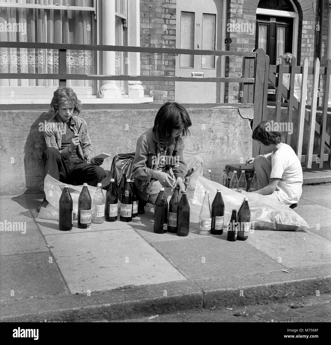 Young boys collecting glass bottles to collect the deposit back and make some pocket money in south London 1970 Stock Photo