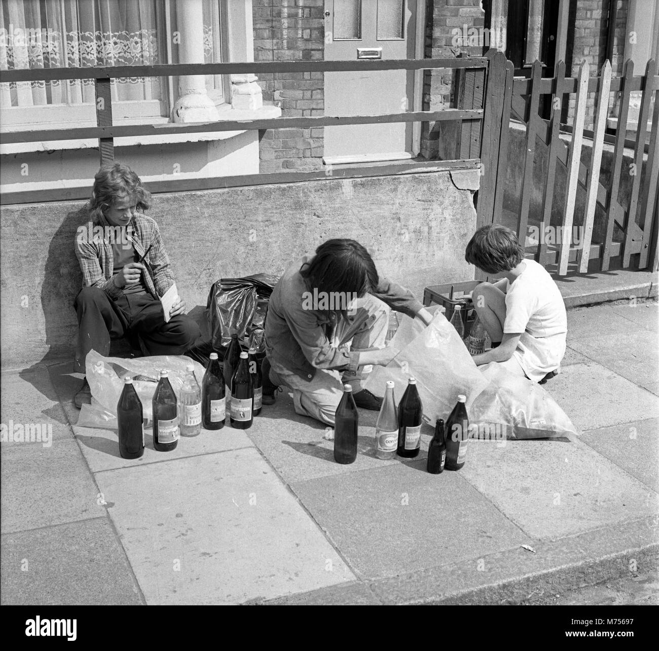 Young boys collecting glass bottles to collect the deposit back and make some pocket money in south London 1970 Stock Photo