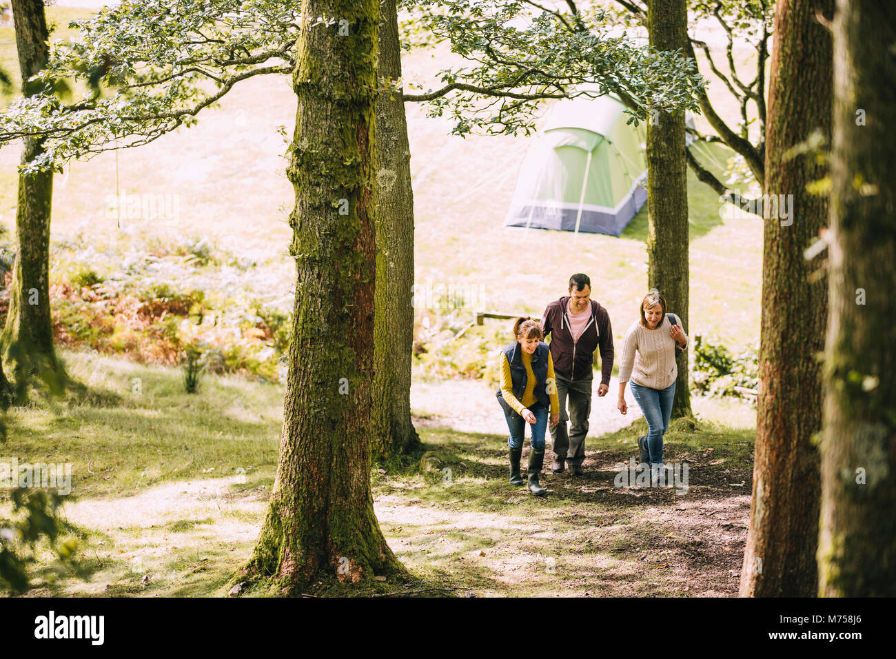 Three mature adults are leaving the campsite to go for a hike together. Stock Photo