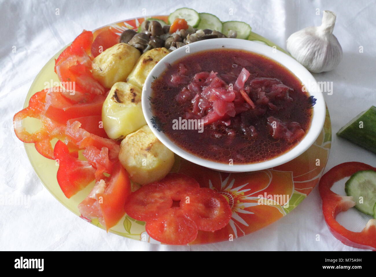appetizing fresh vegetarian dinner soup from beet, roasted potato with mushrooms, ripe juicy tomato, cucumber and pepper prepare for meal Stock Photo