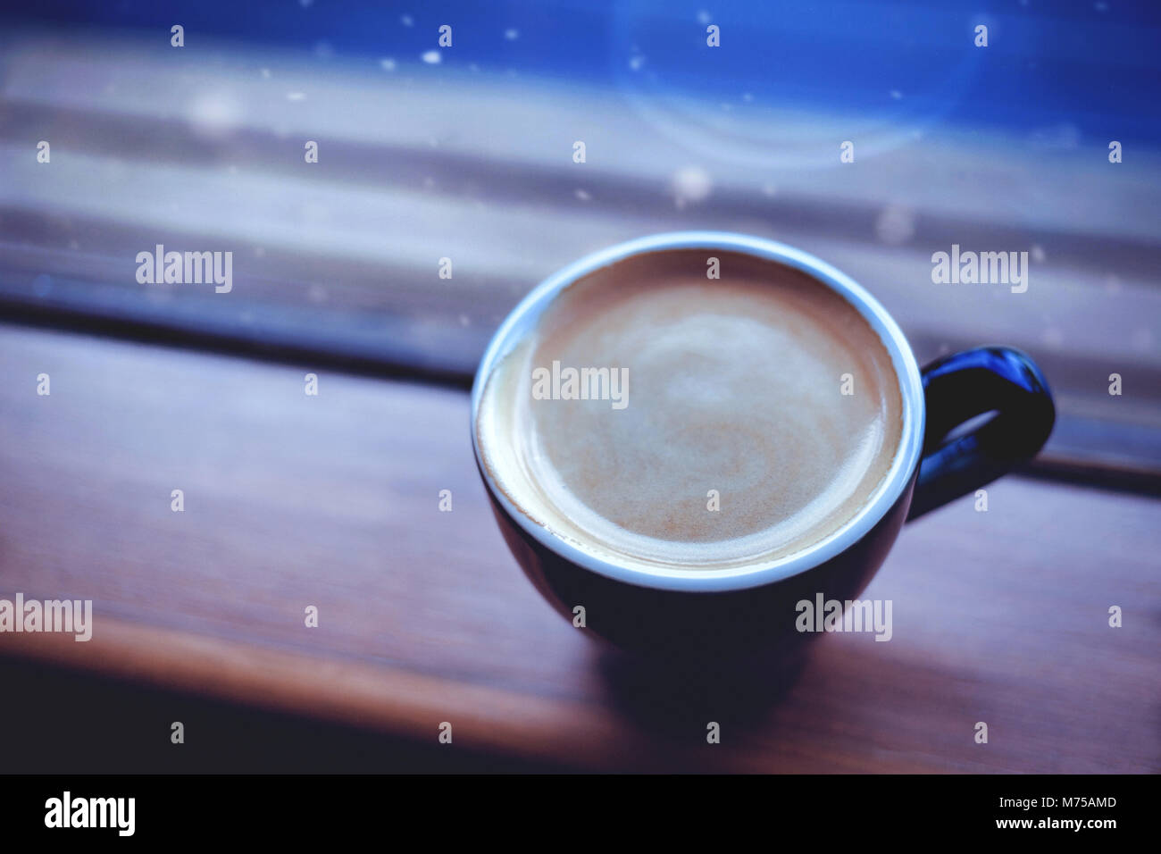 https://c8.alamy.com/comp/M75AMD/americano-coffee-on-a-side-of-the-window-and-snow-falling-in-the-winter-M75AMD.jpg