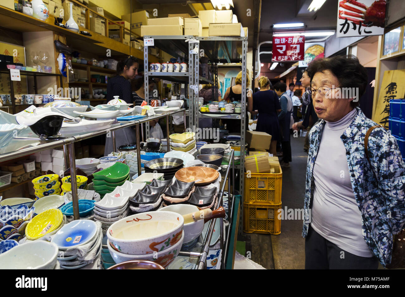Tsukiji, Tokyo, Japan - January 04, 2018 : one senior japanese woman and many tourists are shopping ceramic dishware in traditional kitchenware shop a Stock Photo