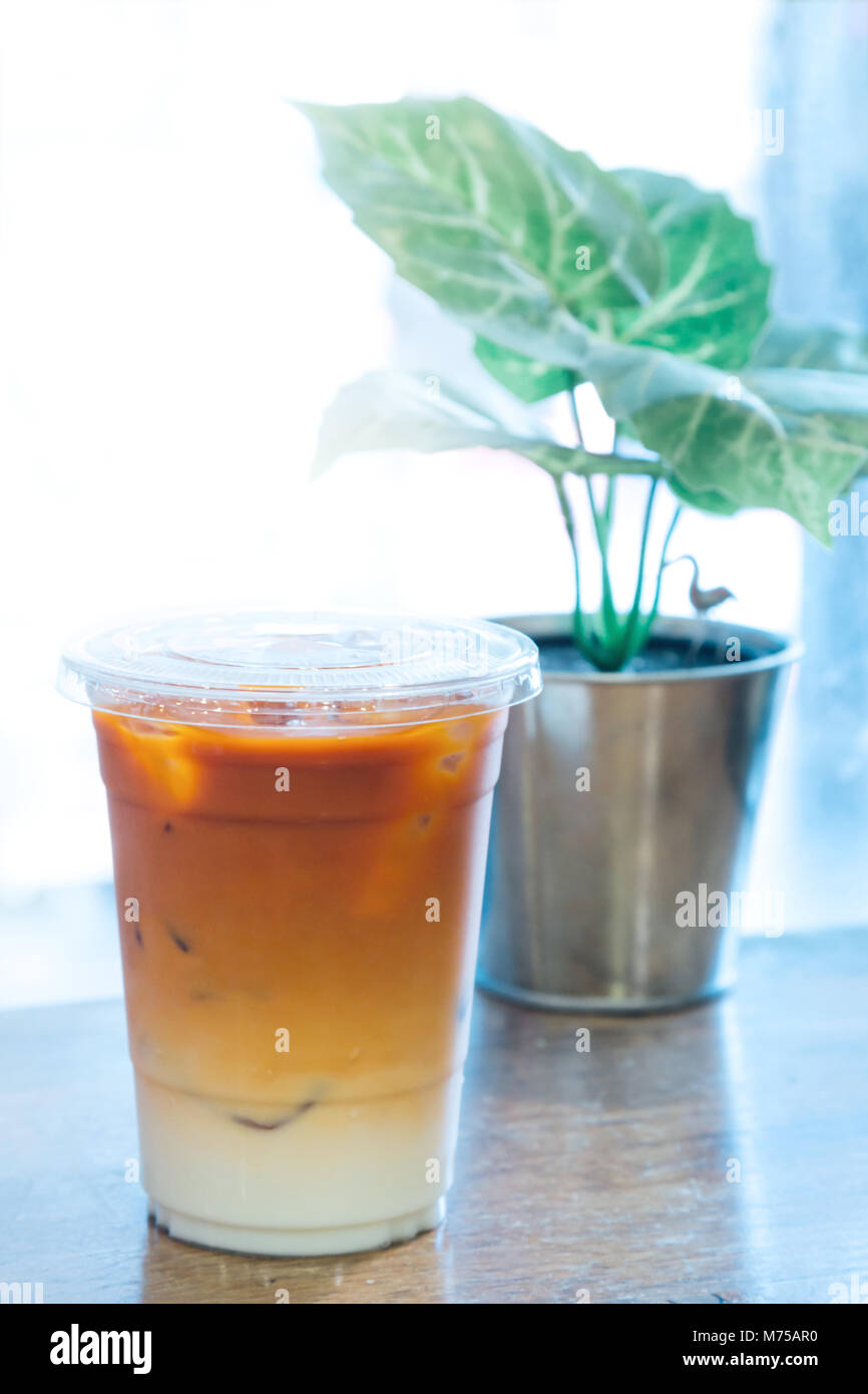 thai tea and fresh milk mixed with ice in the plastic cup at the coffee shop in Thailand ready serve to clients. Ice Thai tea is famous and popular co Stock Photo