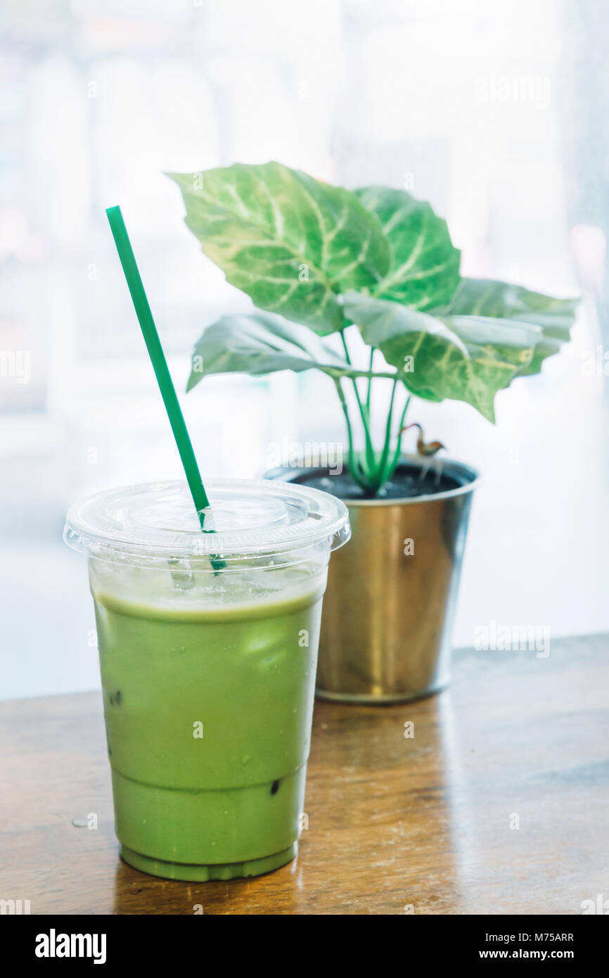 Green tea latte with ice in plastic cup and straw on wooden background.  Homemade Iced Matcha Latte Tea with Milk take away Stock Photo by  ©galitskaya 242393070