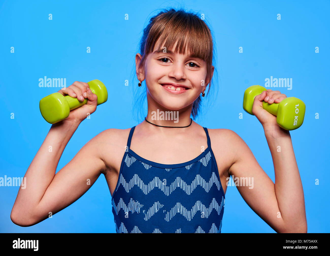 Cheerful little girl wearing sport clothes doing exercises with fitness  ball isolated over blue background Stock Photo - Alamy