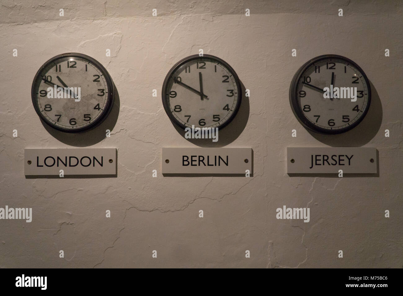 Three clocks on wall depicting time in london,Berlin & Jersey on