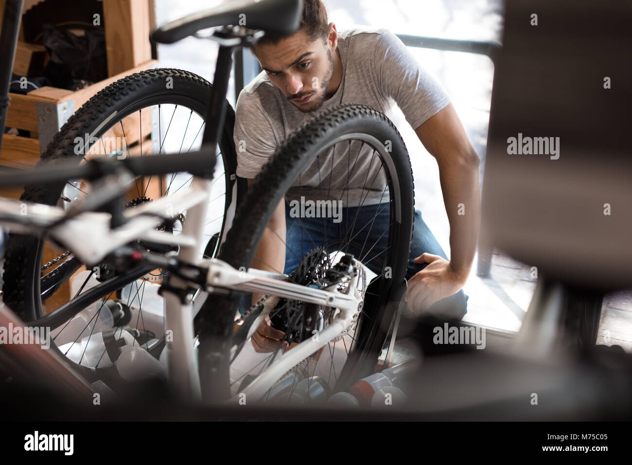 Man inspecting a bicycle wheel for alignment. Mechanic working on