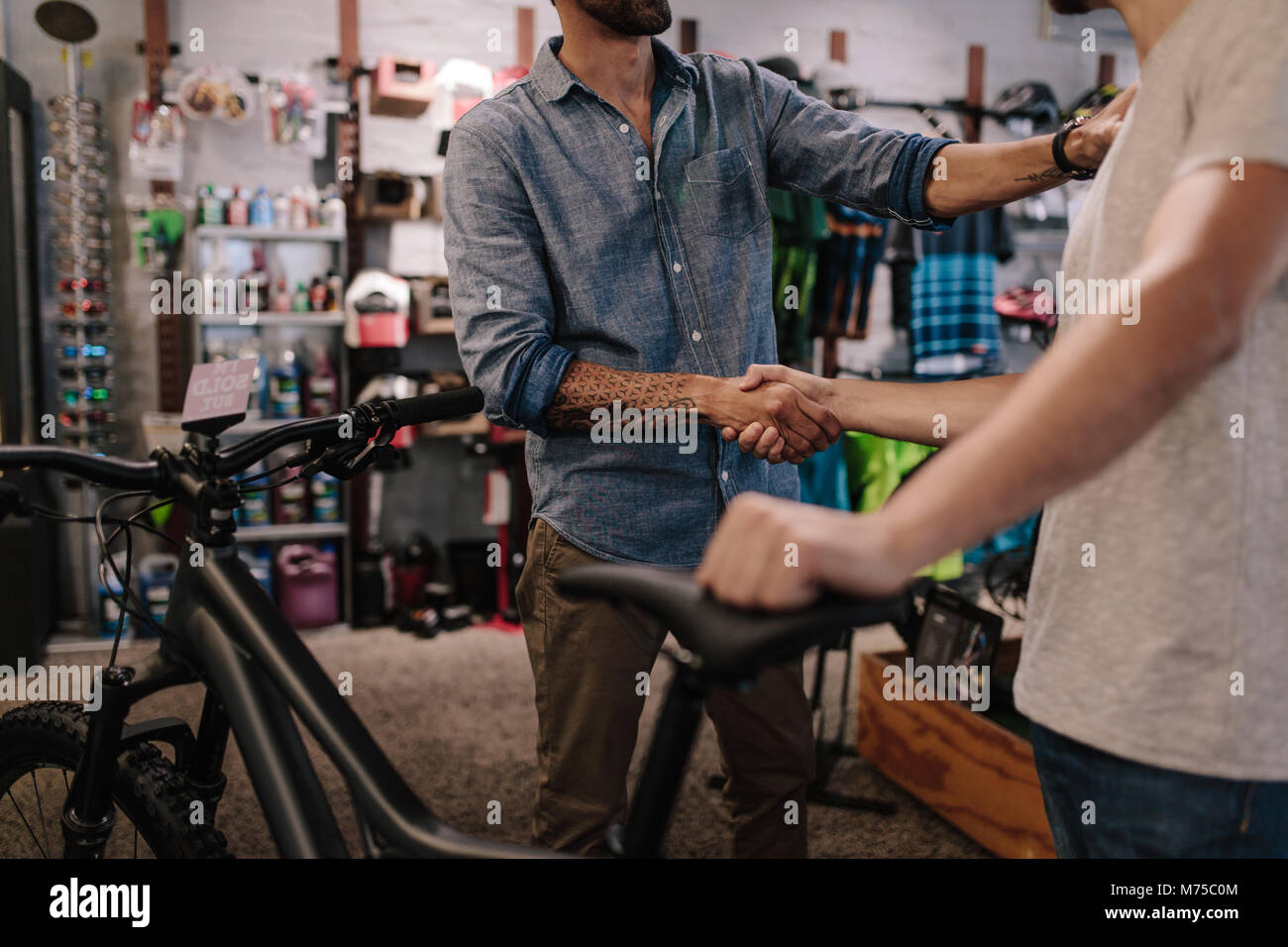 Cropped shot of shop owner giving a handshake to a customer after selling a bicycle. Stock Photo