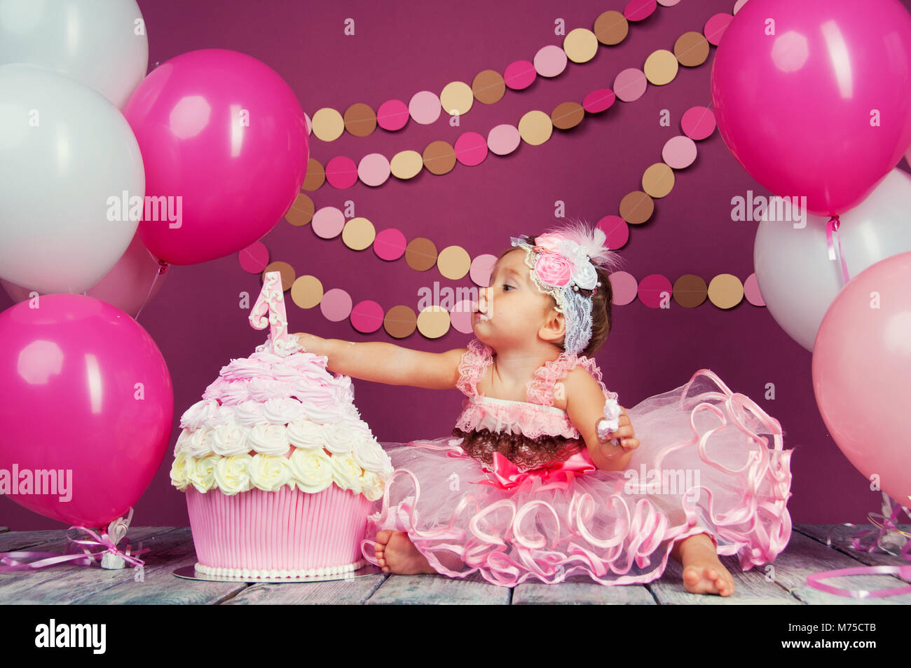 Portrait of a little cheerful birthday girl with the first cake. Eating the first cake. Smash