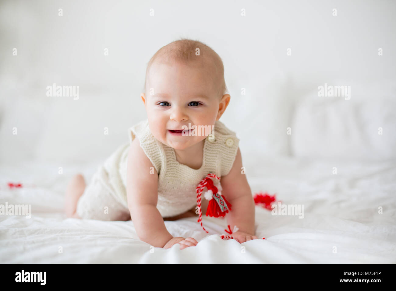 Cute baby toddler boy, playing with white and red bracelets. Martenitsa