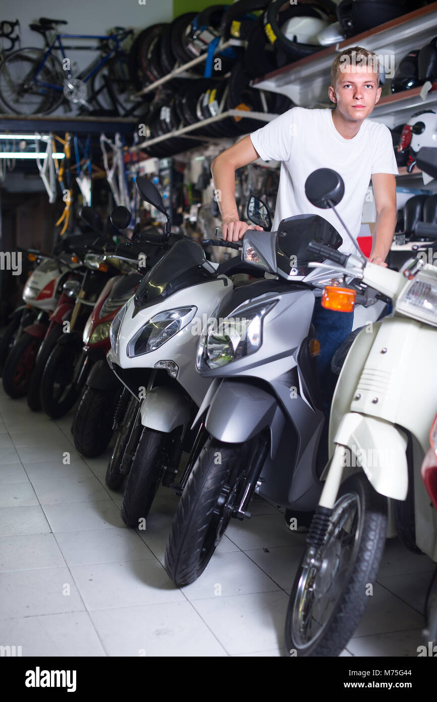 Portrait of positive spanish male motorcyclist sitting on the bike in