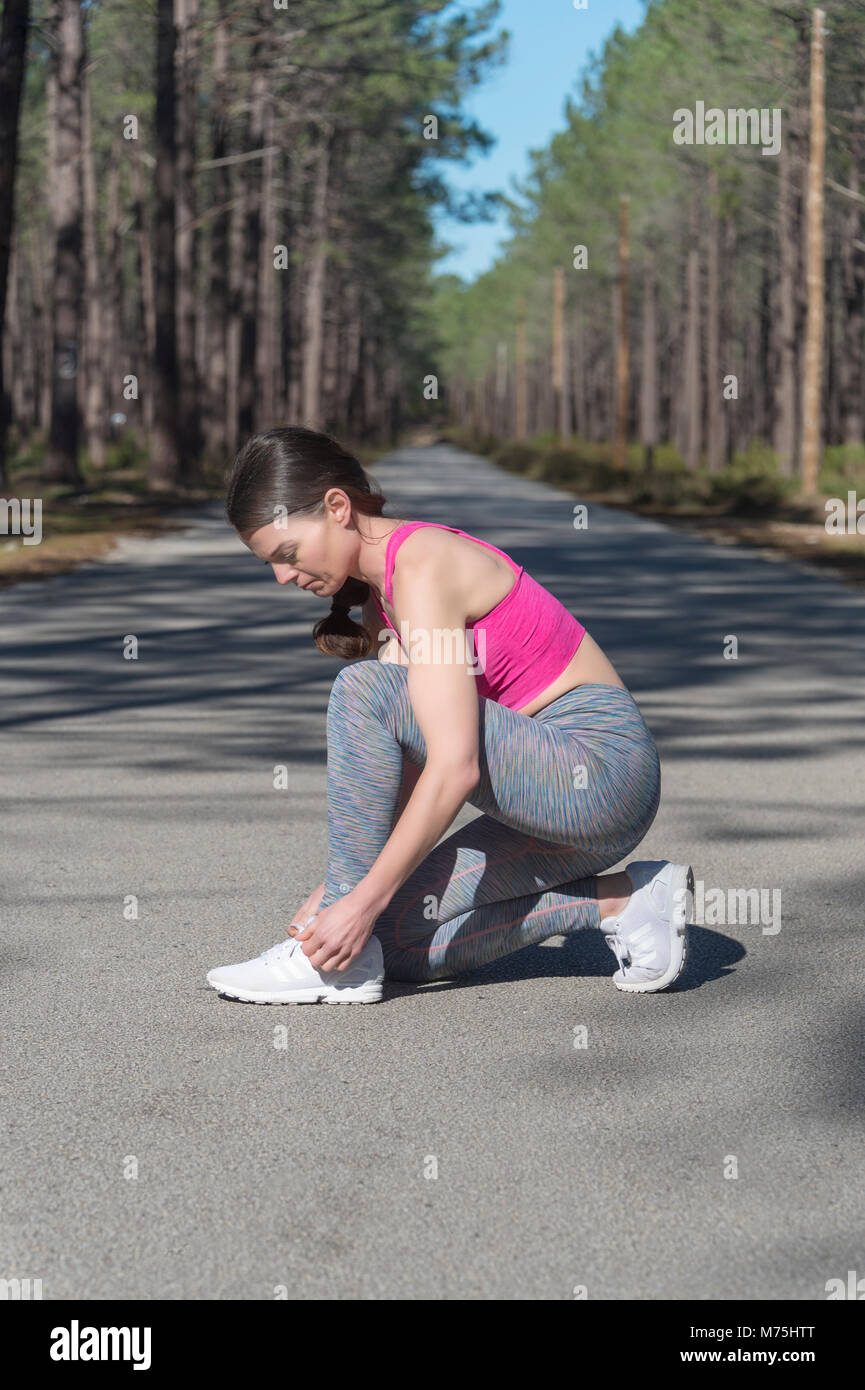 woman jogger tying up her laces on trainers Stock Photo
