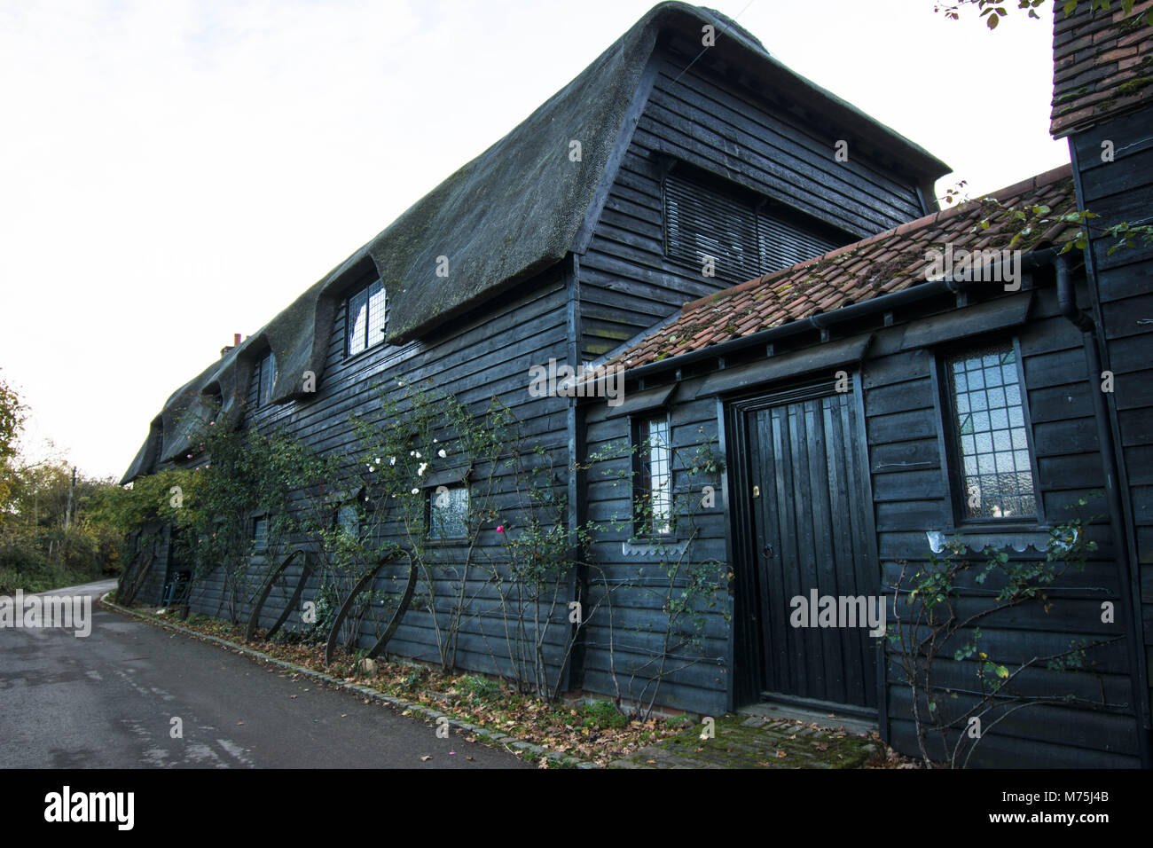 Flatford Mill old barn wood brown old ancient door wheels wheel windows ancient path farmhouse tiles pitched black painted nice village Stock Photo
