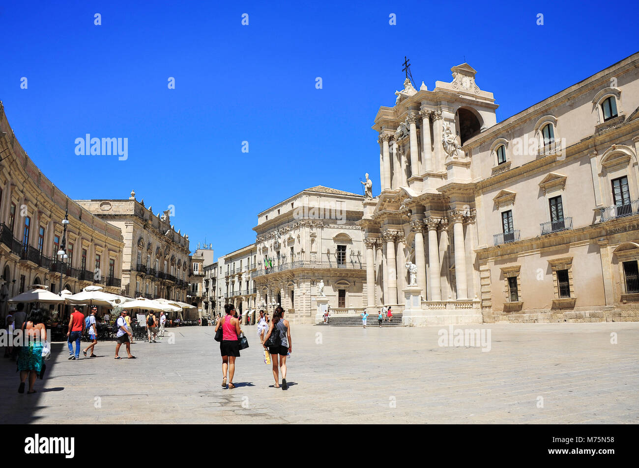Siracuse, Sicily, Italy - Aug 2012: Tourists on main square, Piazza Duomo, Ortigia island, Syracuse. Beautiful architecture with blue sky background Stock Photo