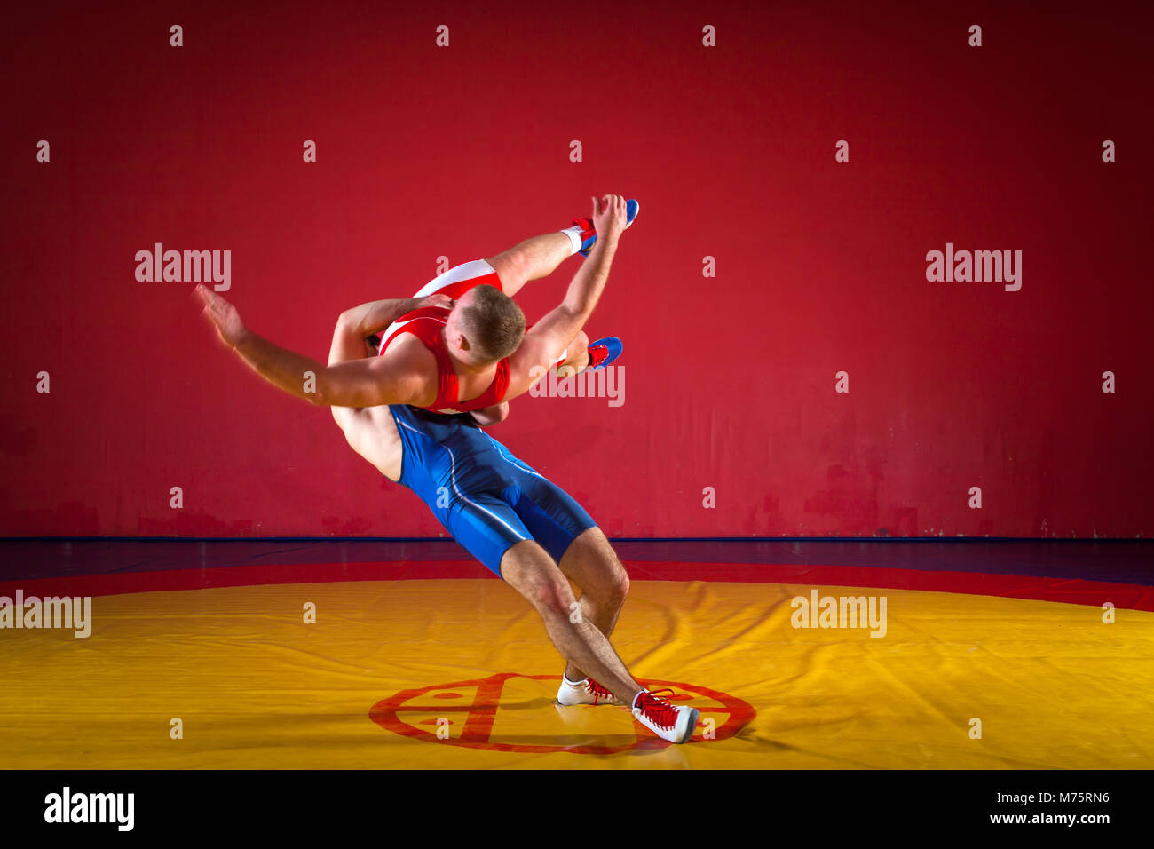 Two young men wrestlers in blue and red wrestling tights are wrestlng