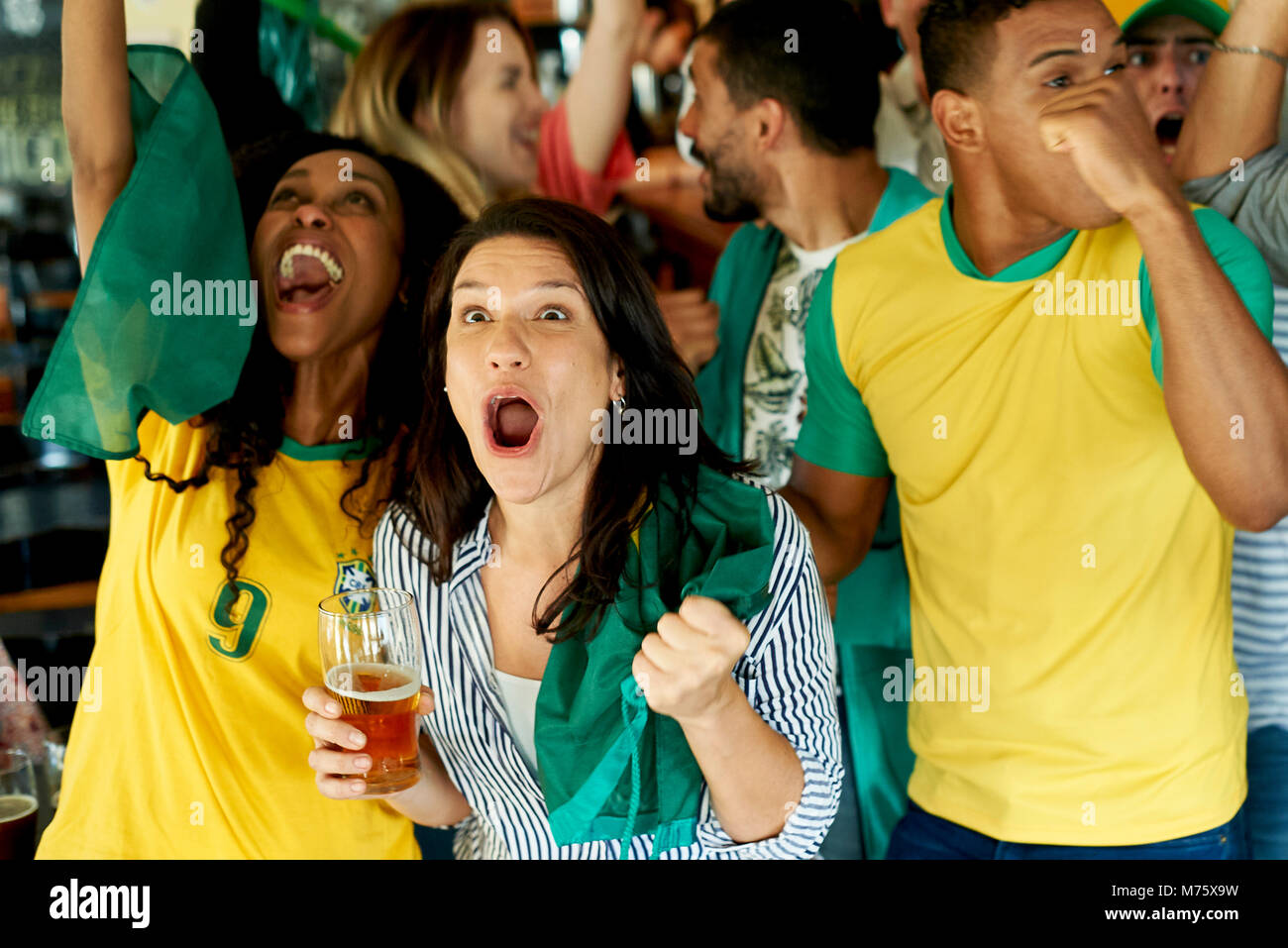 Brazilian soccer fans watching match together at pub Stock Photo