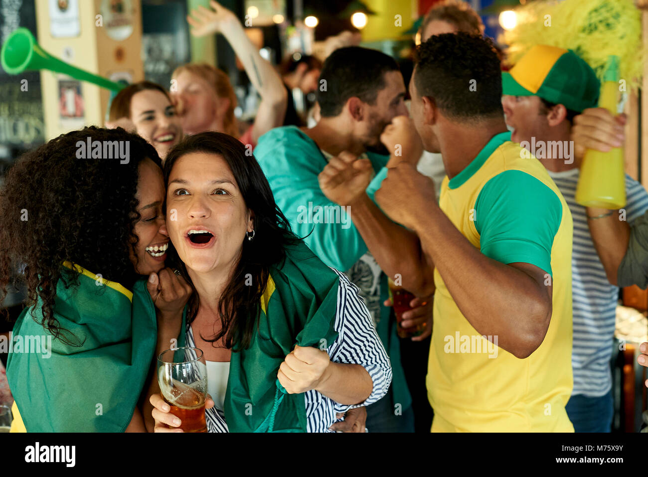 Brazilian soccer fans watching match together at pub Stock Photo
