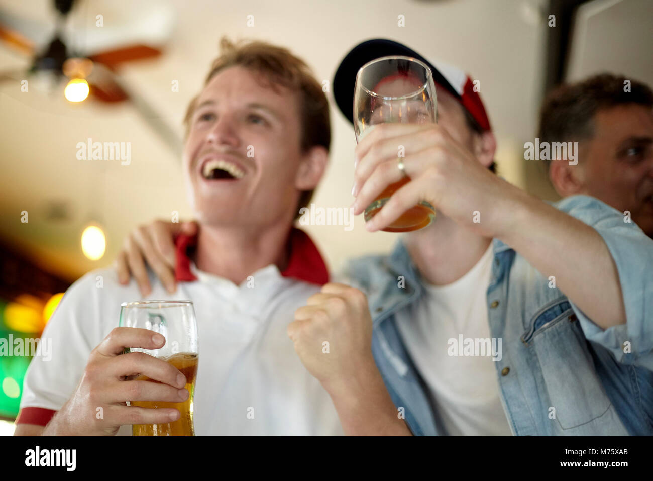 Sports enthusiasts watching match together in bar Stock Photo
