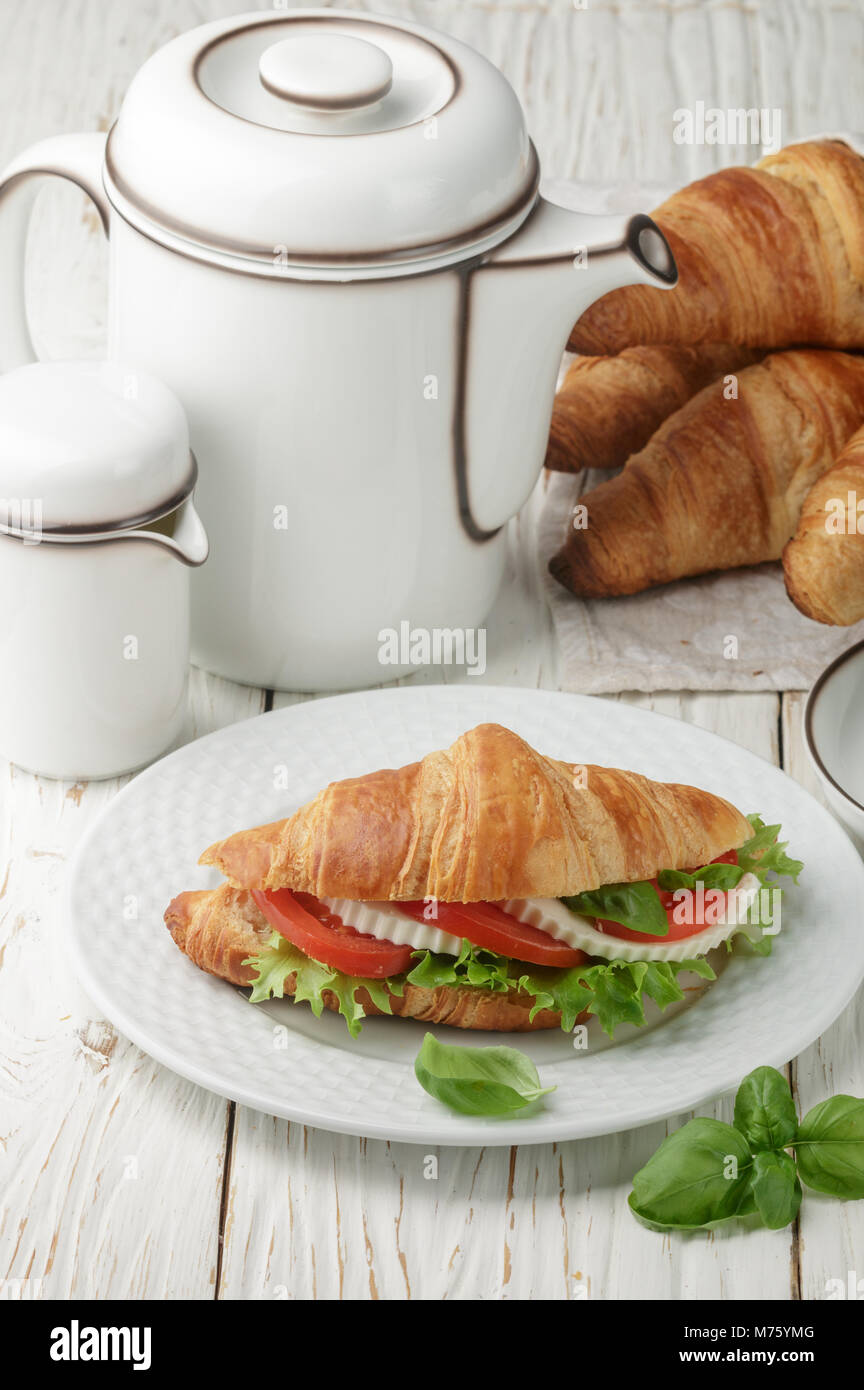 Traditional Breakfast. Croissant Sandwich with tomatoes, cheese, lettuce and Basil. Caprese. Selective focus Stock Photo