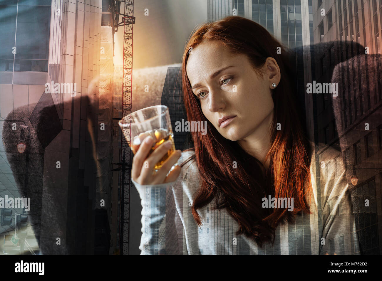 Exhausted depressed woman sitting alone and looking at the glass of alcohol Stock Photo