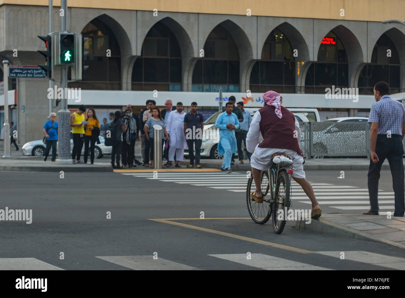 An expat Arab on bycycle at Salam Street / Electra Junction, Crossing Road. Stock Photo